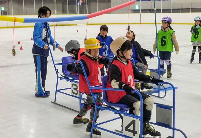 ソリに乗って、氷上パン食い競争にチャレンジする参加者。