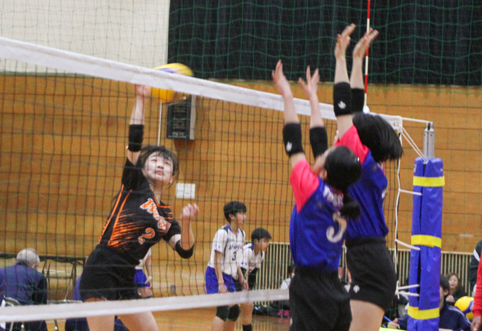 スパイクを打とうとする選手と、ブロックするためジャンプする選手。