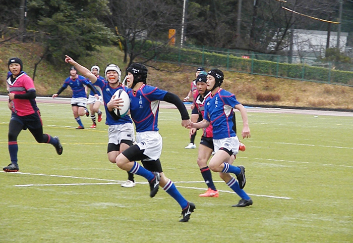 ボールを抱えて走る試合中の選手